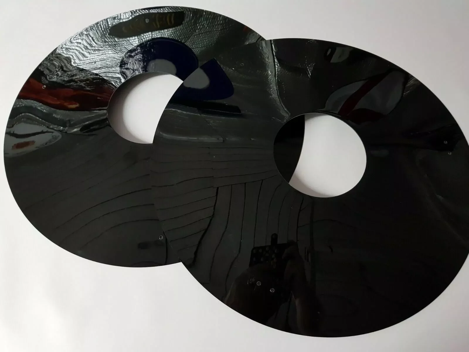 Two blank black wheelchair spoke guards, showing their centre openings and small pre-drilled fixing holes.
